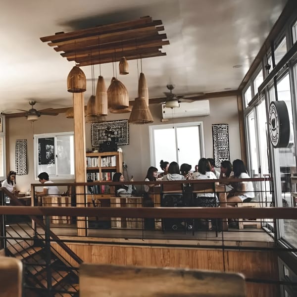 Customers seated in a rustic, multi-level dining area with wooden decor and large windows.