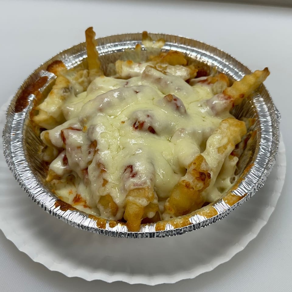 Cheesy fries in a foil container, topped with melted mozzarella cheese and a hint of sauce.